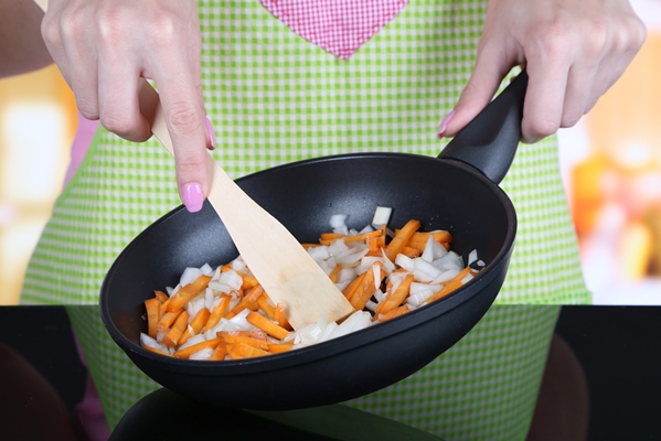 hands cooking fried onion with carrot in pan in kitchen - Черемша по-корейски