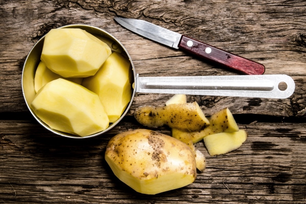 peeled potatoes in an old pan with knife on wooden table - Щавелевые щи по-монастырски