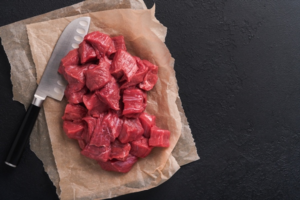 raw chopped beef meat raw organic meat beef or lamb spices herbs on old parchment paper on dark grey concrete background goulash raw uncooked meat meat with blood top view with copy space - Мясо, тушённое со снытью и щавелем