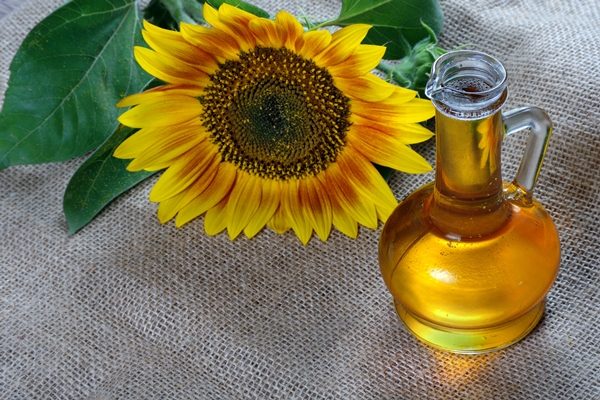 sunflower oil and a sunflower flower on the table natural vegetable oil - Жареный корень лопуха