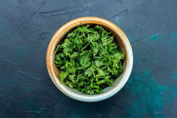 top view fresh greens inside round pot on dark blue desk - Голубцы с черемшой
