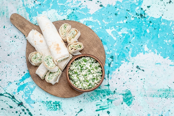 top view tasty vegetable rolls whole and sliced with greens filling and cabbage salad on the bright blue desk food meal roll vegetable snack lunch - Рулетики из сныти с творогом
