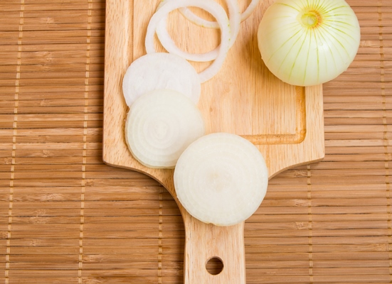 bulb onions sliced on wooden cutting board top view - Куриное филе, запечённое по-французски