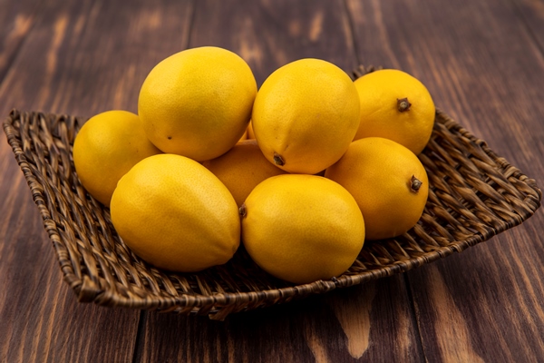 top view of fresh yellow lemons on a wicker tray on a wooden wall - Лимонная закуска