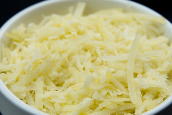 grated cheese in a white pot isolated selective focus top view macro - Запеканка из капусты