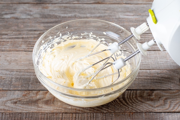 butter in a glass bowl with a mixer making cake cream - Вафельный торт со сгущёнкой