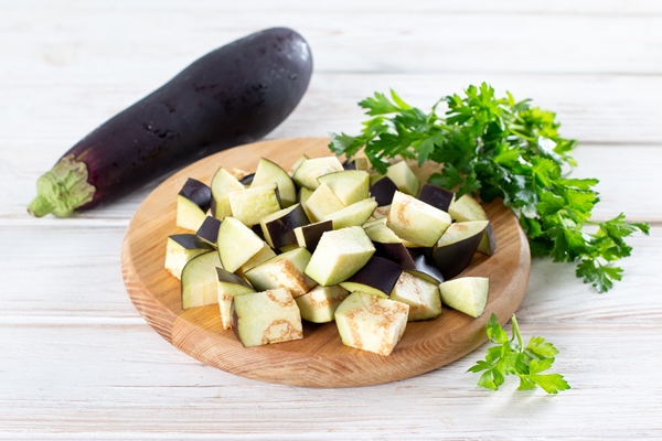 chopped eggplant and knife on cutting board on wooden table - Овощной суп с баклажанами и чечевицей