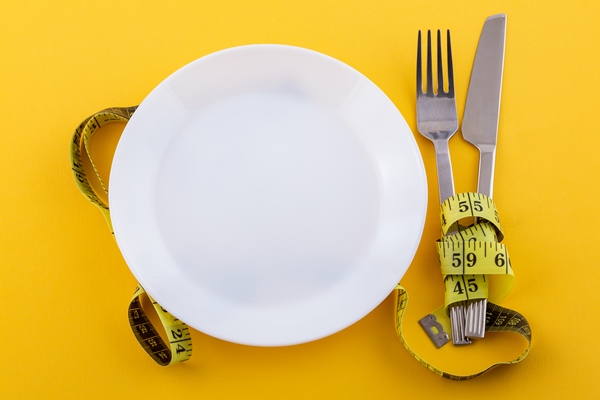 cutlery and a white plate with measuring tape on a yellow the concept of weight loss and diet - Растительное молоко: виды и свойства