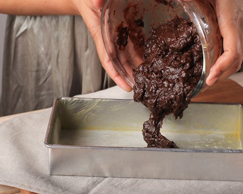 female pouring chocolate batter to prepared baking pan step by step baking in the kitchen bakery concept - Шоколадно-миндальный брауни