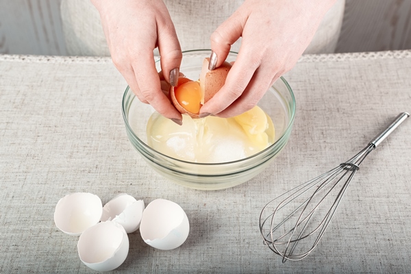 hands breaking an egg over a glass bowl of sugar - Домашнее печенье "Персики"