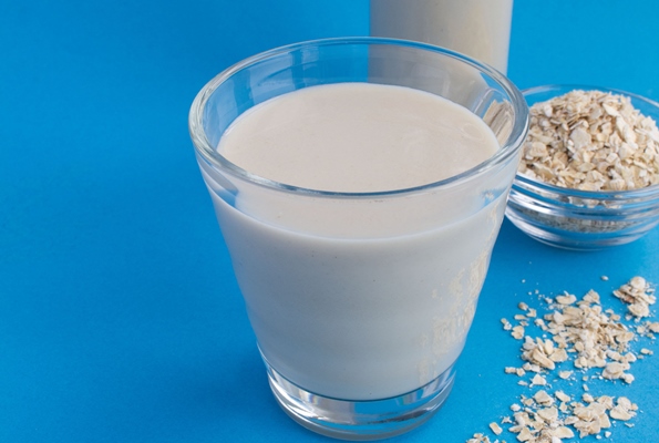 oat milk in the glass on the blue background healthy drink - Растительное молоко: виды и свойства