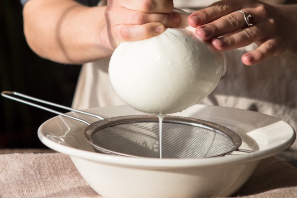 preparation of coconut milk woman straining the milk through a cheesecloth preparation of almond milk from soaked and peeled nuts vegan milk alternative concept - Кокосовое молоко