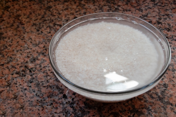 white rice soaked in water ready to cook in a bowl - Рисовое молоко двумя способами