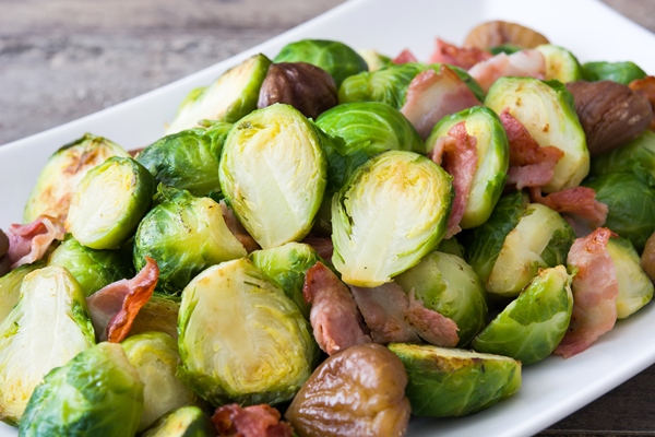 brussels sprouts with chestnuts and bacon on wooden table close up - Брюссельская капуста с беконом и каштанами