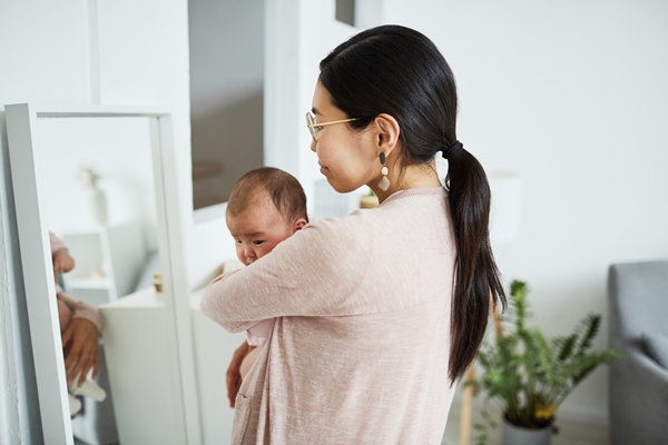 rear view of young woman holding her baby and looking at mirror while standing in the room - Съедобные водоросли