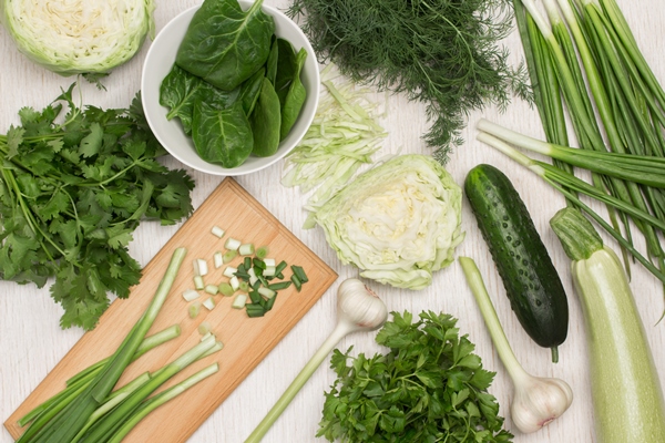 set of greens and vegetables green onions on cutting board cabbage and zucchini bunch of parsley dill and cilantro on table white background flat lay - Зелёный кефир