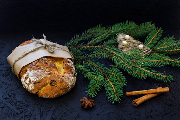 traditional german christmas pastry stollen on a black background with fir spices - Масляный рождественский штоллен