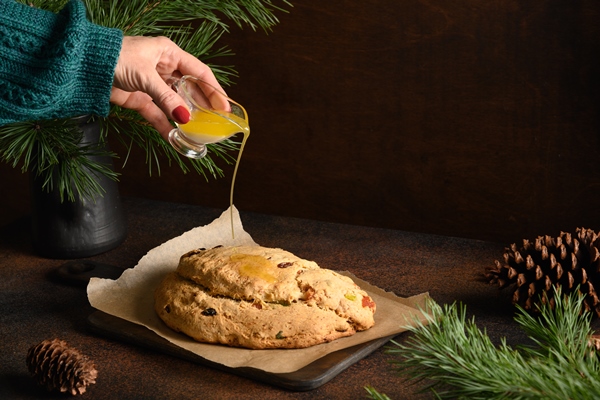 woman pouring butter on christmas stollen on a brown background - Масляный рождественский штоллен