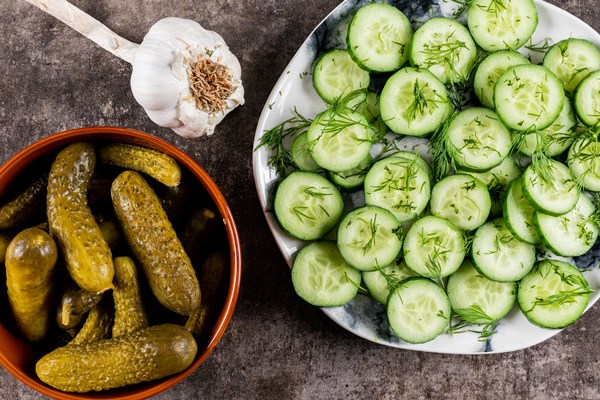 top view cucumber fresh sliced with dill on plate and pickled in bowl on brown stone - Картофель с огурцами в горшочке