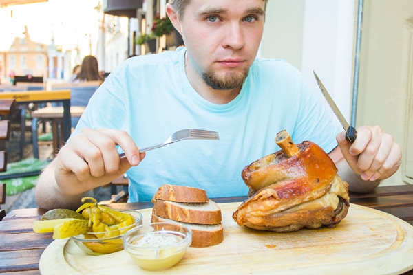 young man eating smoked pork leg meat and drinking beer - Русский столовый хрен