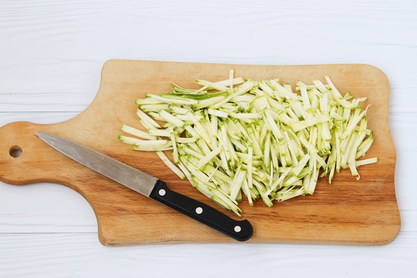 zucchini cut into thin strips arranged on a wooden board on white background top view - Мойва с овощами в горшочках