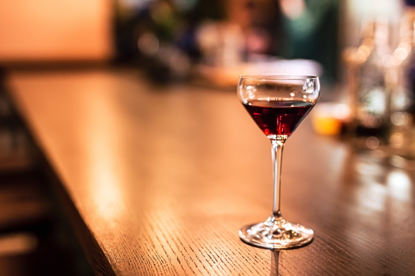 a coupe glass with red port wine at the bar counter a horizontal lifestyle photo with shallow depth of field and copy space - Камберлендский соус (английская кухня)