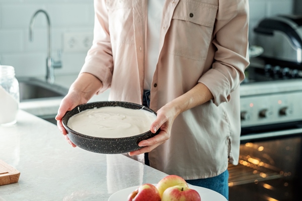 a woman in the kitchen holds a baking dish with a dough for making a pie with apples cooking food baking from rice flour - Пирог "Мечта" с яблоками