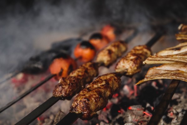 close up view of lula kebab on metal skewers on dark wall - Люля-кебаб