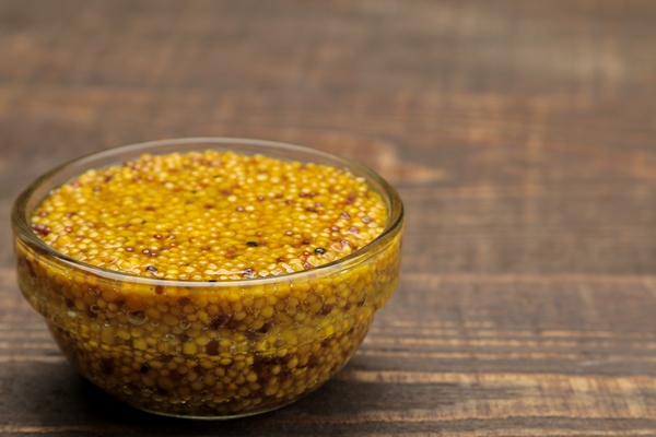 french mustard mustard sauce with grains in a glass bowl on a brown wooden stand close up - Баранина по-индийски