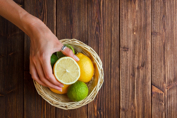 some lemons with hand holding half of lemon in a basket on wooden background top view - Камберлендский соус (английская кухня)