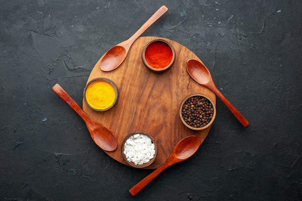 top view turmeric red pepper black peper sea salt in smal bowls four spoons on round board on dark table with copy space - Турецкая запеканка с кебабом