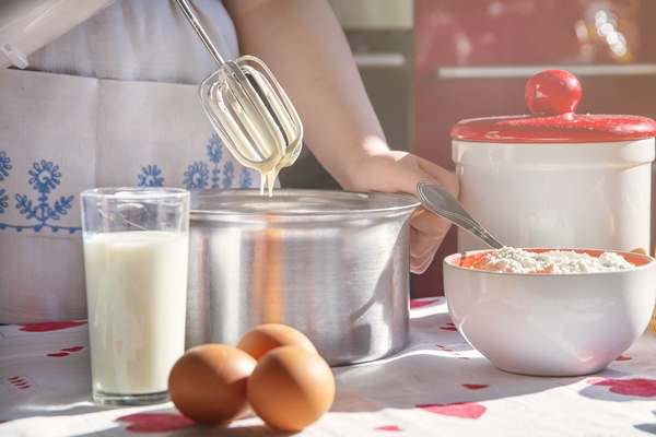 a girl in a white apron makes pancake batter with a mixer in a metal pan - Японские блины дораяки