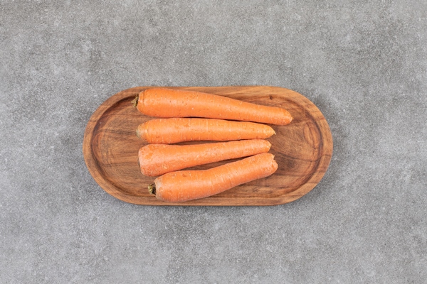 a wooden board of fresh sweet carrots placed on a stone surface - Печёночные котлетки на пару (для детей до 1 года)