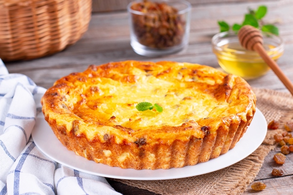 cheese casserole with raisins on plate on wooden table close up - Творожная запеканка с манкой, изюмом и молоком