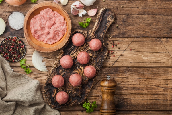 fresh beef raw meatballs on wooden board with mince on bowl plate with pepper salt and garlic on wooden background - Мясное пюре для питания детей до 1 года