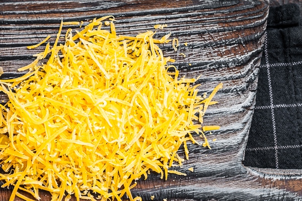 grated and diceded cheddar cheese on a wooden chopping board dark wooden background top view - Кукурузные маффины с халапеньо