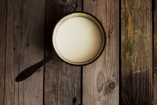 overhead view of fresh milk in an old saucepan over the wooden table - Овощной суп с сыром для детей до 1 года