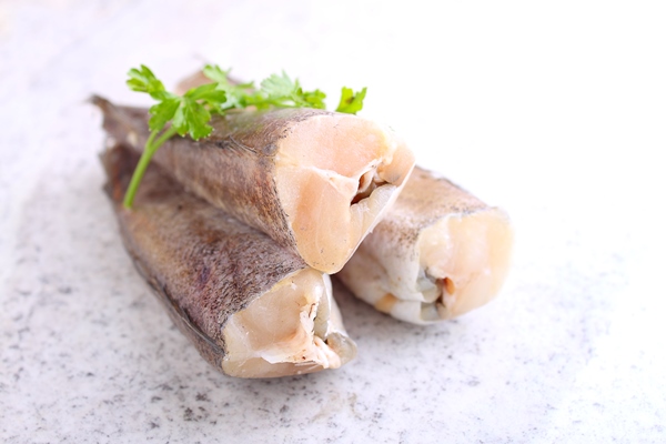 raw fish hake in white packaging decorated with parsley - Суфле из хека для питания детей до 1 года