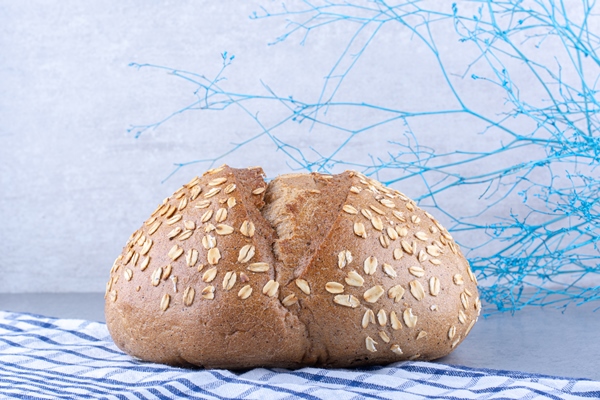 towel under a flake coated bread on marble surface - Хлеб из цельнозерновой муки