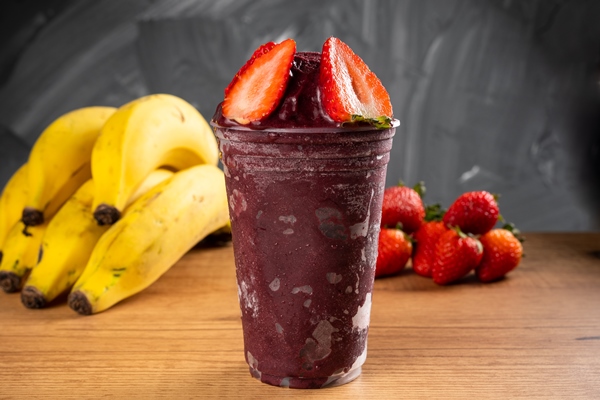 brazilian frozen aa ai berry ice cream smoothie in plastic cup with strawberries on a wooden desk and a gray summer background with fruits front view for menu and social media - Постный смузи-боул "Щербет"