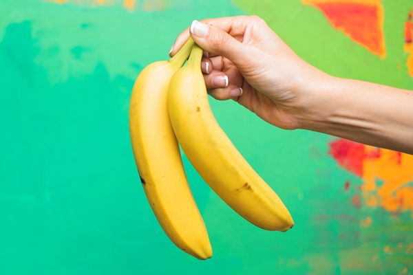 close up woman with bananas and colourful background - Постный смузи-боул из бананов, яблок и шпината