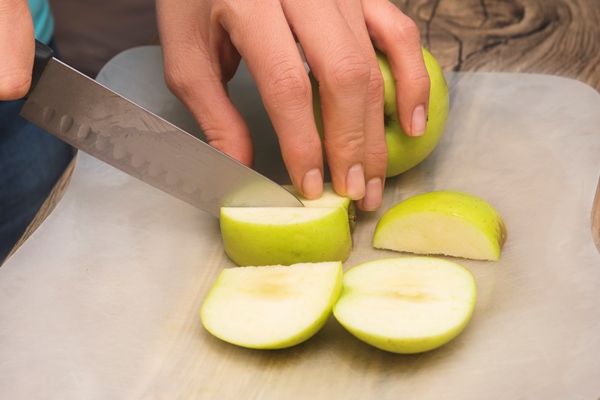 closeup of hands on latin girl cutting green apples - Постный смузи-боул из бананов, яблок и шпината