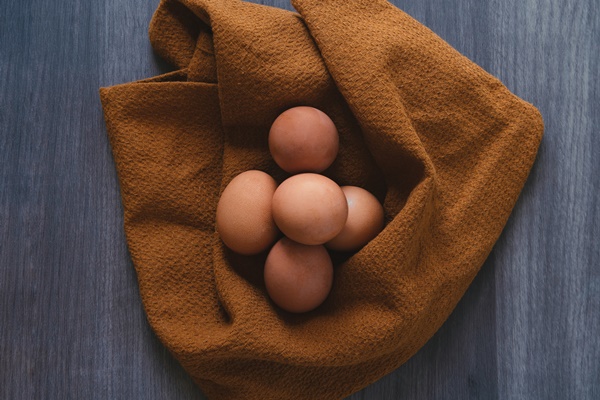 five fresh eggs on a rustic wooden table and wrapped in kitchen towel - Вафельные трубочки