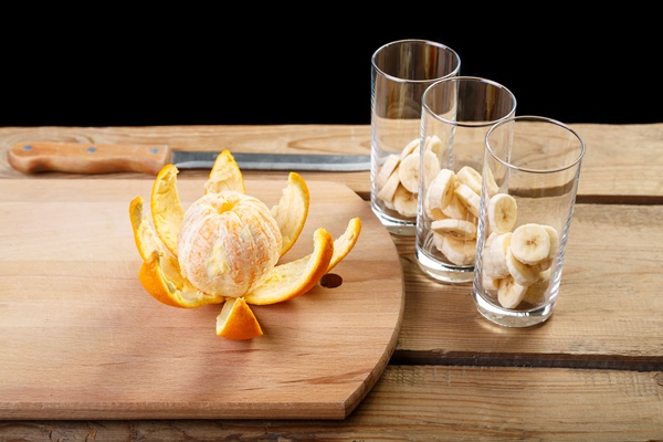 on a wooden table there is a peeled orange and three glasses with bananas for a cocktail - Постный смузи-боул с ягодами асаи