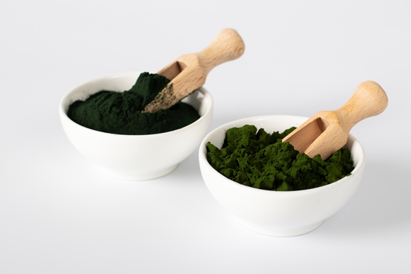 organic algae chlorella and spirulina in powder form in white bowls with wooden scoops on white background - Правила приготовления смузи-боулов