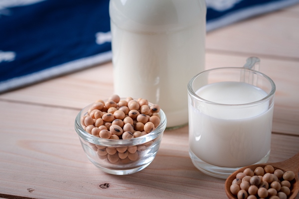 soybean seeds in glass bowl and milk in glass bottle on wooden table - Постный малиновый смузи-боул