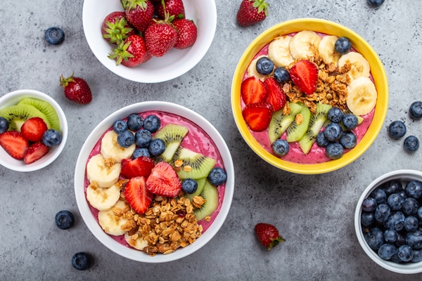 summer acai smoothie bowls with strawberries banana blueberries kiwi fruit and granola on gray concrete background breakfast bowl with fruit and cereal close up top view healthy food - Постный смузи-боул с бананом, киви, клубникой, голубикой