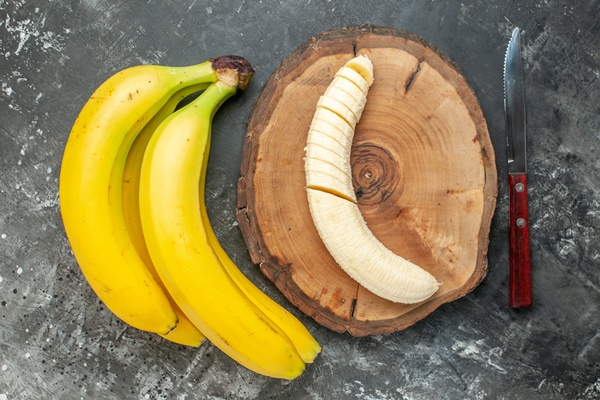 top view nutrition source fresh bananas bundle and chopped on wooden cutting board knife on gray background - Постный смузи-боул "Щербет"