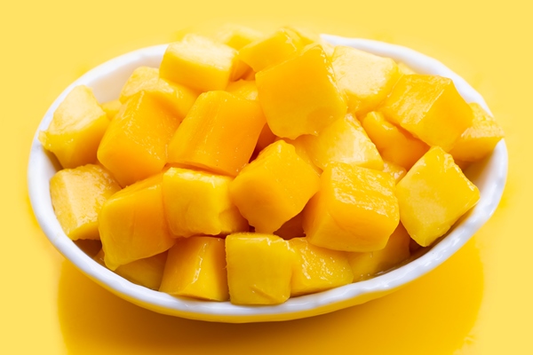 tropical fruit mango cube slices in white bowl on yellow background - Постный смузи-боул с манго и ореховой пастой