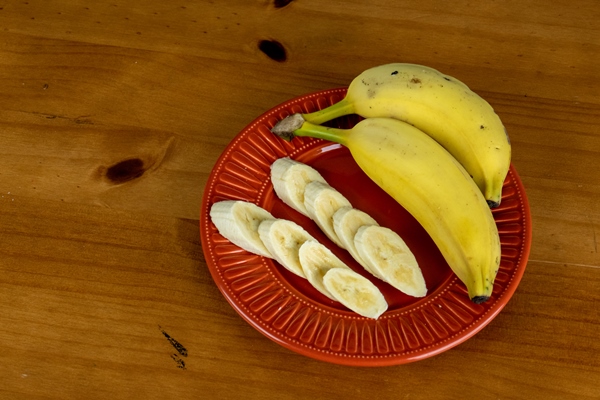 delicious yellow banana served in an orange plate on the wooden table - Смузи-боул с хурмой и семенами чиа